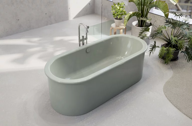 Freestanding oval steel-enamel bathtub in soft green in modern bathroom with plants.