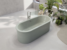 Freestanding oval steel-enamel bathtub in soft green in modern bathroom with plants.