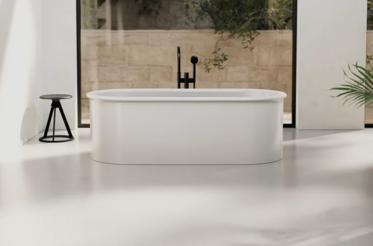 Freestanding oval steel-enamel bathtub in front of large windows in minimalist bathroom.
