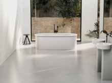 Freestanding oval bathtub made of steel enamel in modern bathroom with washbasin and countertop, bright surroundings.