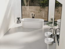 Freestanding oval bathtub made of steel enamel, two round washbasins on countertop, modern bright bathroom.